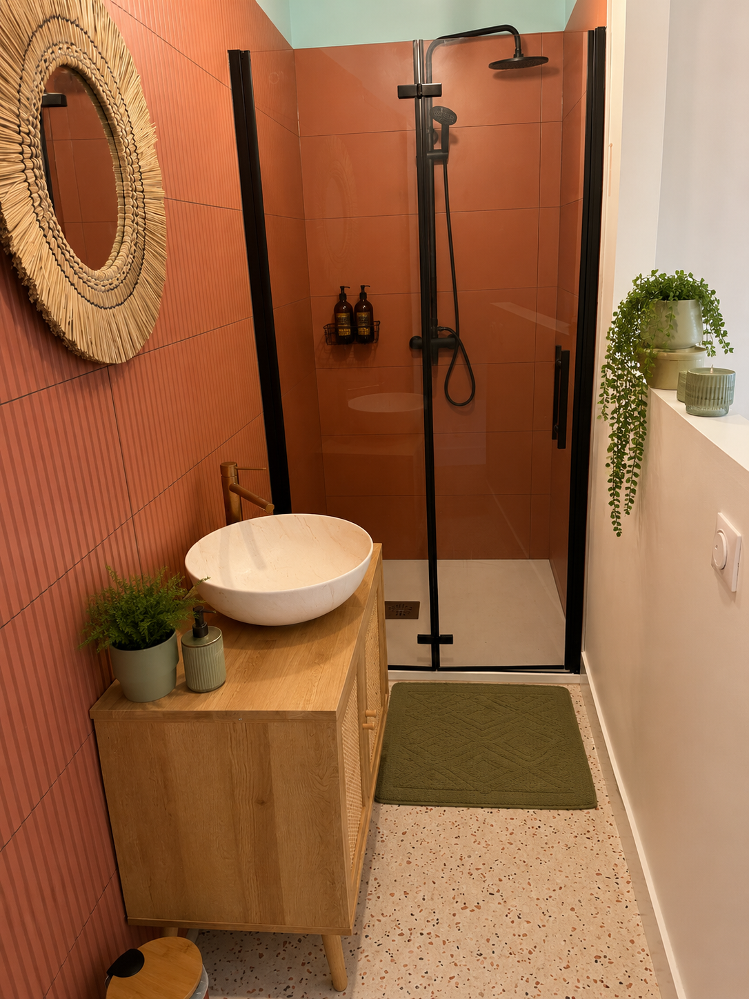 Salle d'eau terra avec douche, vasque en pierre et détails noir mat